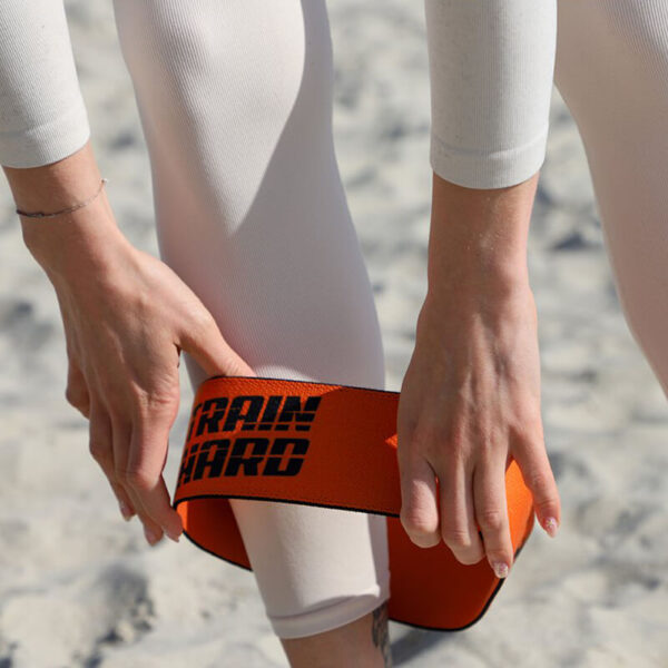 Close-up of hands placing custom printed resistance band on legs before exercise.