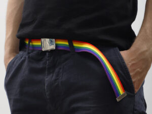 Model wearing branded rainbow belt with sublimated logo as part of a casual outfit.